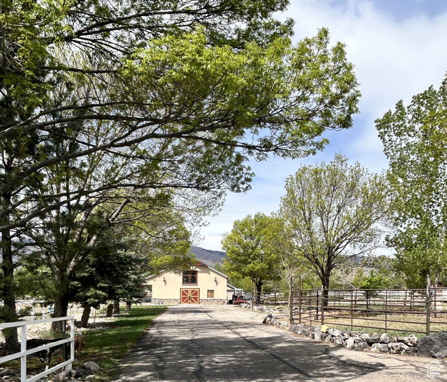 View of front of home featuring an outdoor structure, stucco siding, fence, and a barn