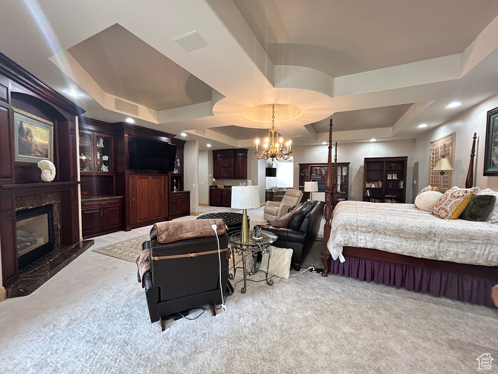 Bedroom with a tray ceiling, visible vents, a chandelier, carpet floors, and a premium fireplace