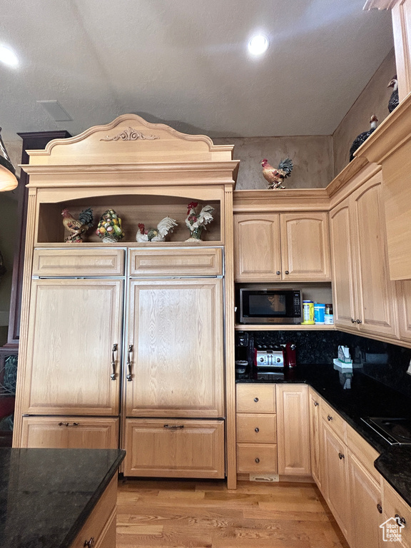 Kitchen with light wood finished floors, open shelves, light brown cabinets, and built in microwave