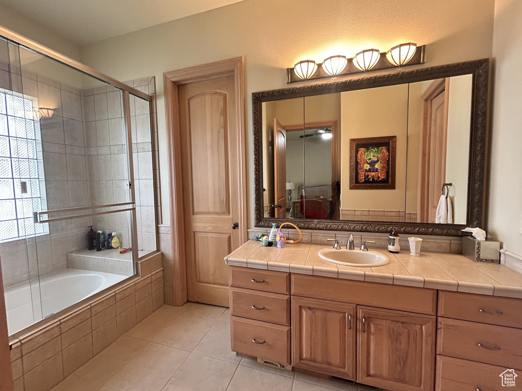Full bathroom with tile patterned flooring, tiled tub, tiled shower, and vanity