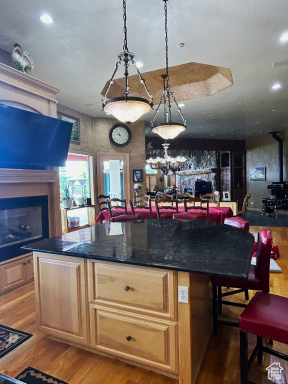 Kitchen with light wood-style floors, a kitchen island, a fireplace, and recessed lighting
