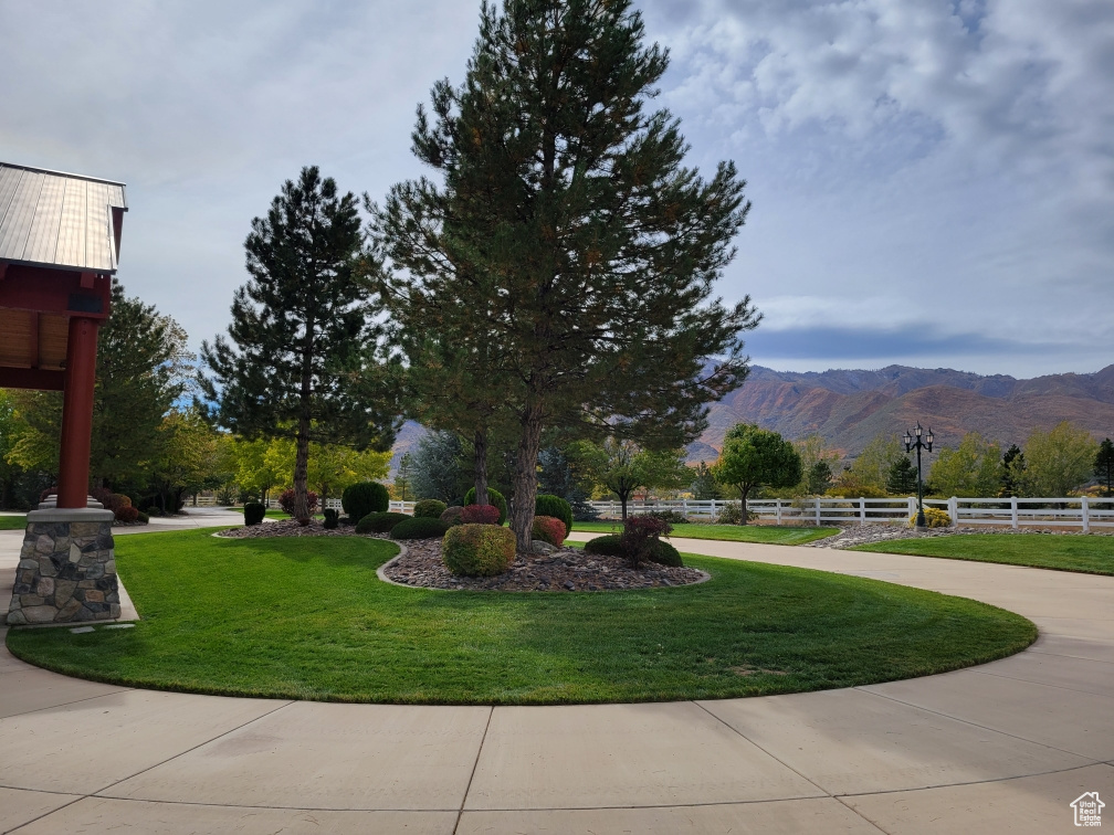 View of property's community with a mountain view, fence, and a lawn