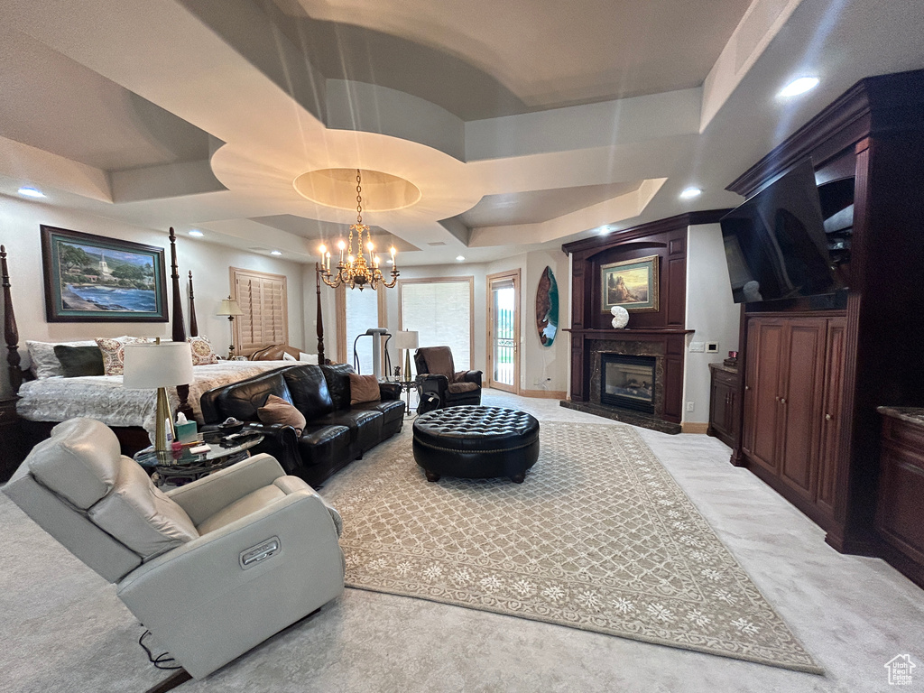 Living room featuring a high end fireplace, a raised ceiling, an inviting chandelier, and recessed lighting