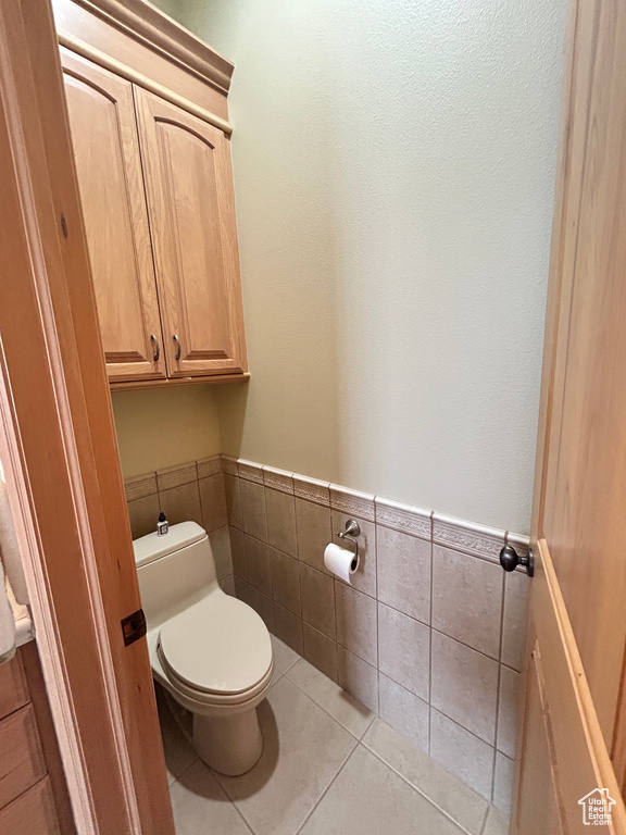 Bathroom with wainscoting, tile patterned flooring, tile walls, and toilet