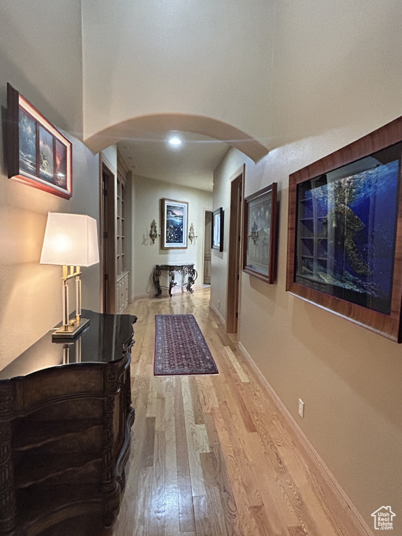 Corridor with built in features, wood finished floors, baseboards, and arched walkways