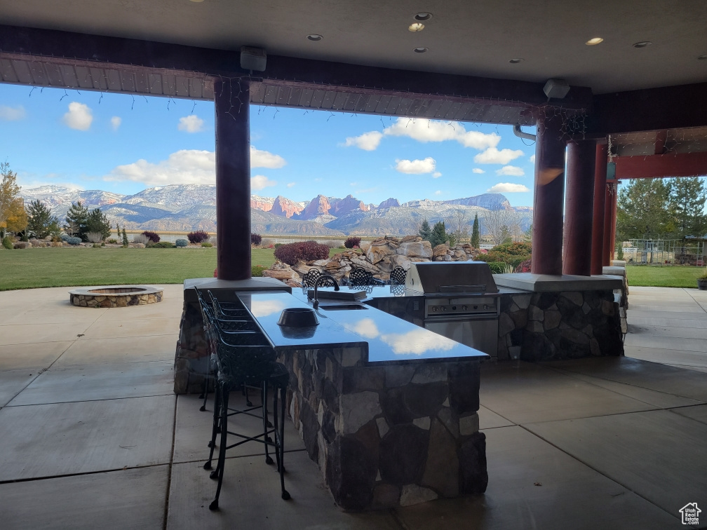 View of patio / terrace featuring area for grilling, a mountain view, a grill, outdoor wet bar, and a fire pit
