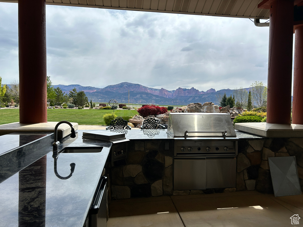 View of patio / terrace with outdoor wet bar, exterior kitchen, a sink, and a mountain view