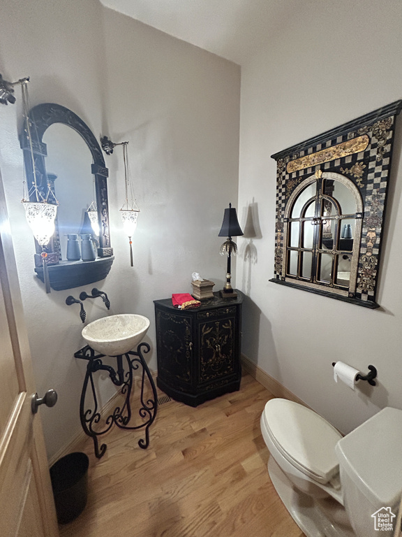 Bathroom featuring toilet, baseboards, and wood finished floors