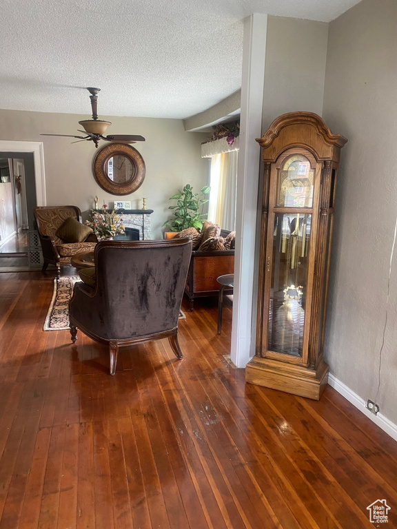Living room featuring a textured ceiling, wood-type flooring, and a ceiling fan