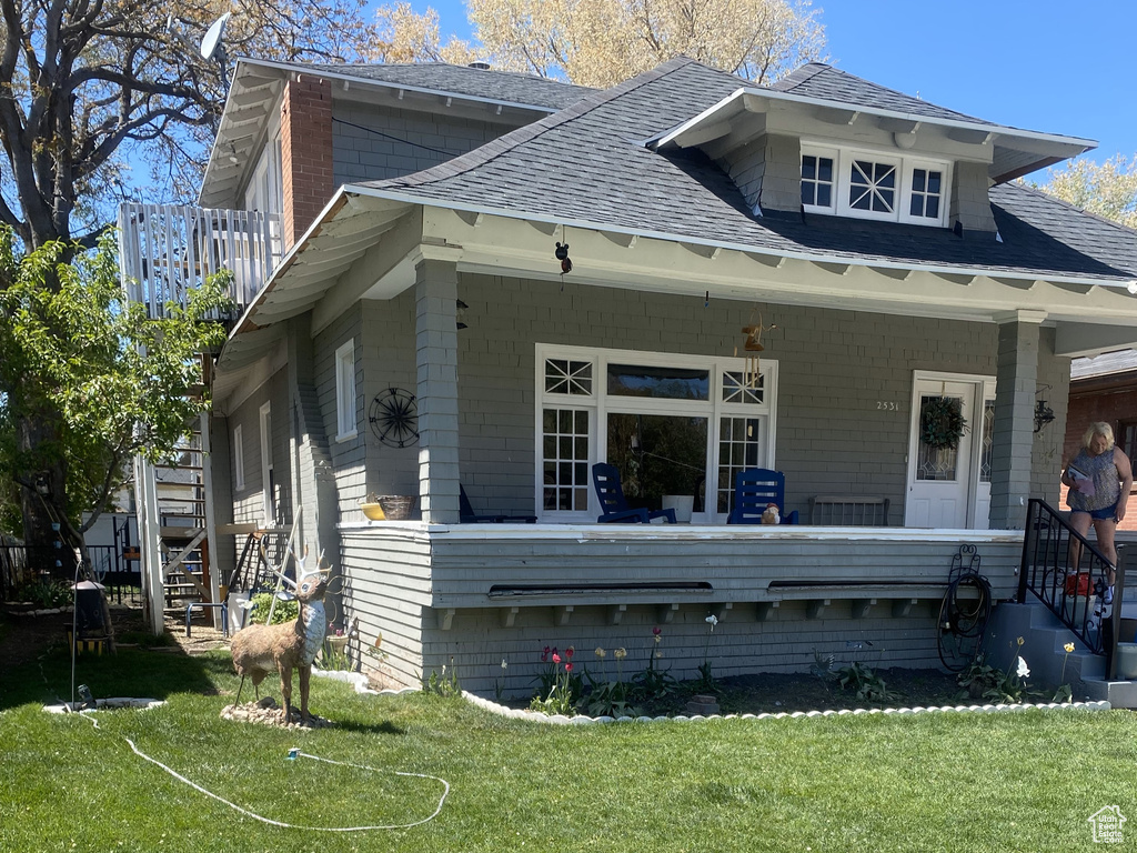 Exterior space featuring covered porch, a front yard, and a shingled roof