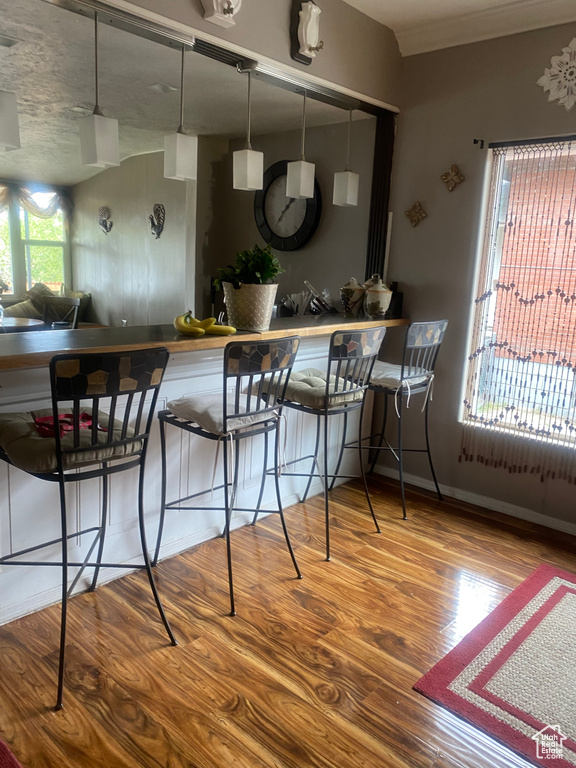 Kitchen featuring baseboards, a kitchen bar, and wood finished floors