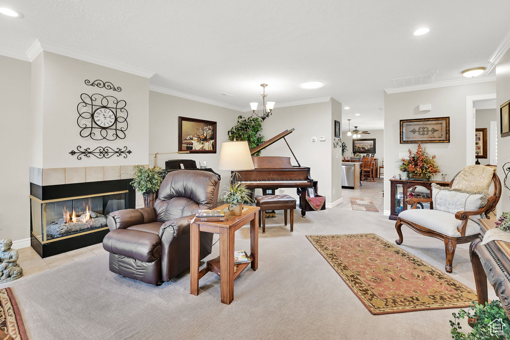 Living room with a chandelier, crown molding, baseboards, a tile fireplace, and recessed lighting