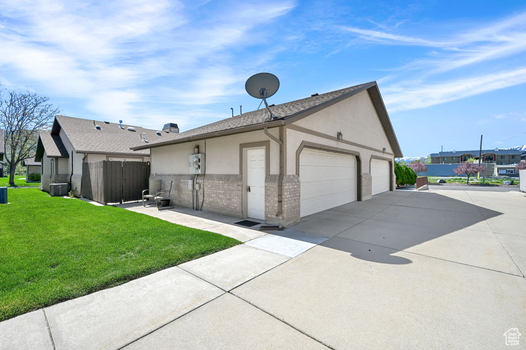 View of side of home featuring cooling unit, stucco siding, brick siding, and a shingled roof