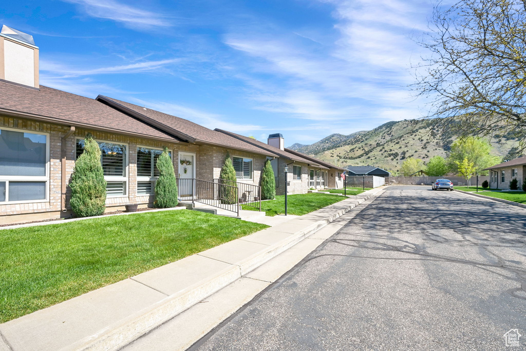 View of front of home with a chimney, a mountain view, brick siding, and a residential view