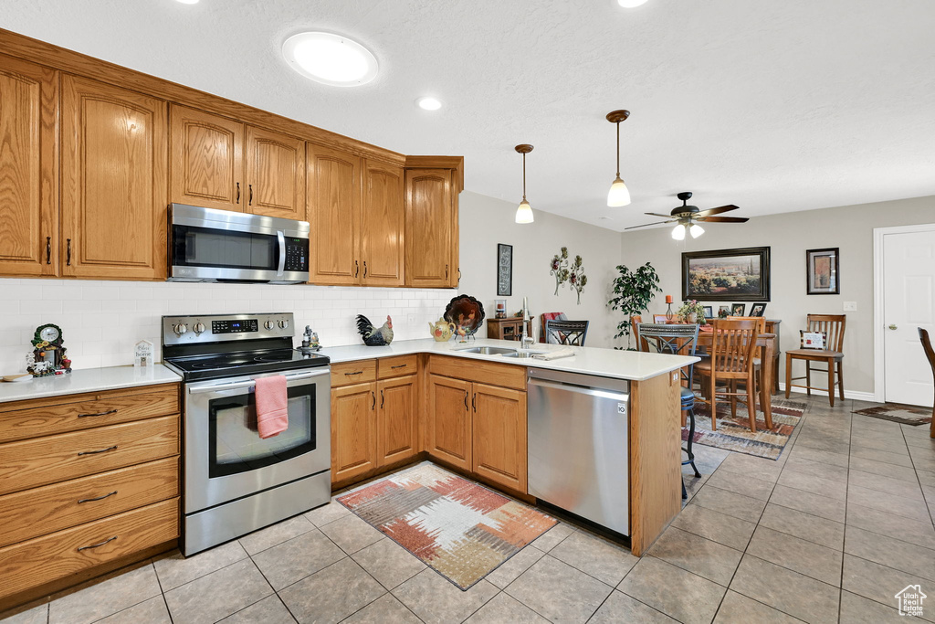 Kitchen featuring stainless steel appliances, ceiling fan, backsplash, light countertops, and light tile patterned flooring