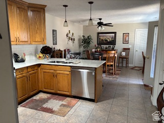 Kitchen featuring a peninsula, light countertops, stainless steel dishwasher, and brown cabinets