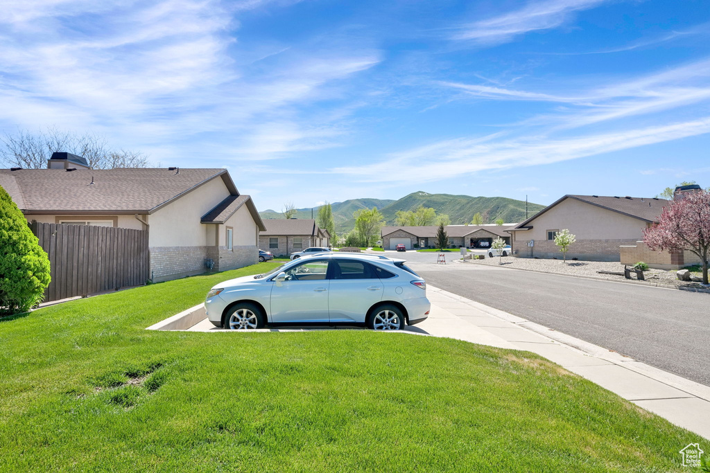 View of asphalt street featuring a mountain view, a residential view, and curbs
