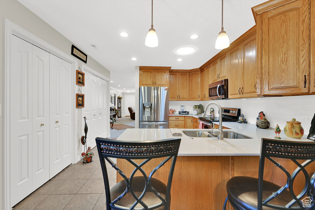 Kitchen with appliances with stainless steel finishes, light countertops, a peninsula, a breakfast bar area, and recessed lighting