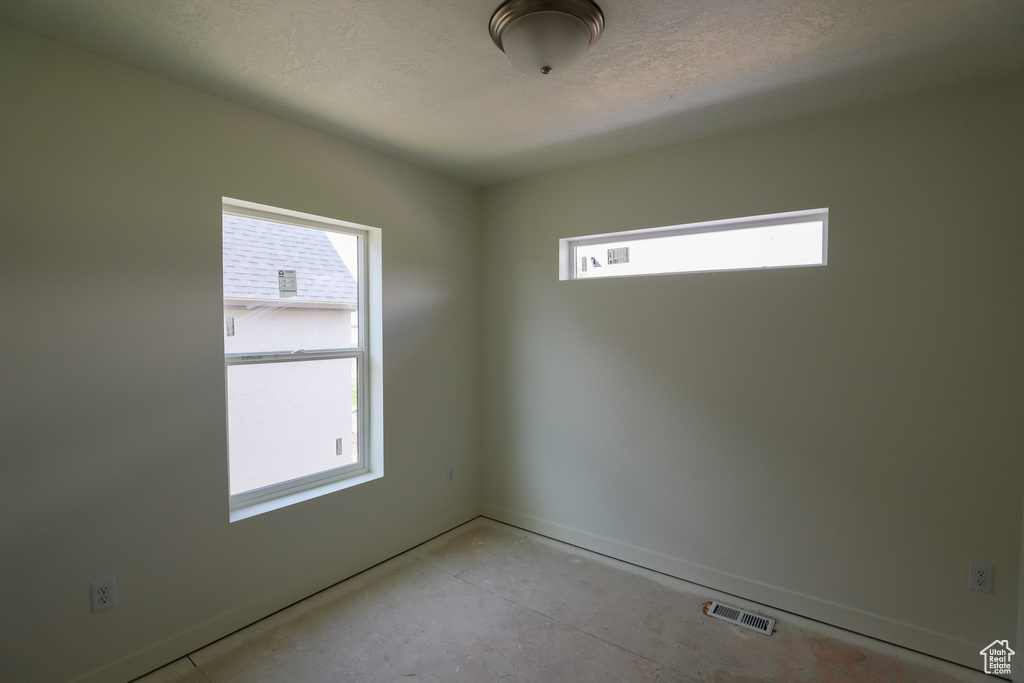 Spare room featuring a textured ceiling, baseboards, and visible vents