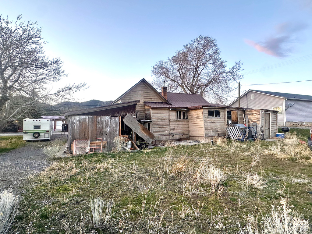 Rear view of property with a chimney and metal roof