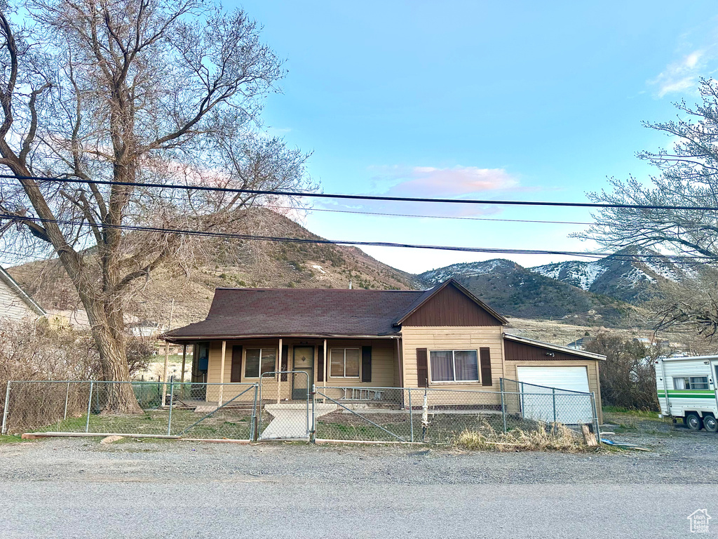 View of front of house featuring a porch, a fenced front yard, a mountain view, and an attached garage