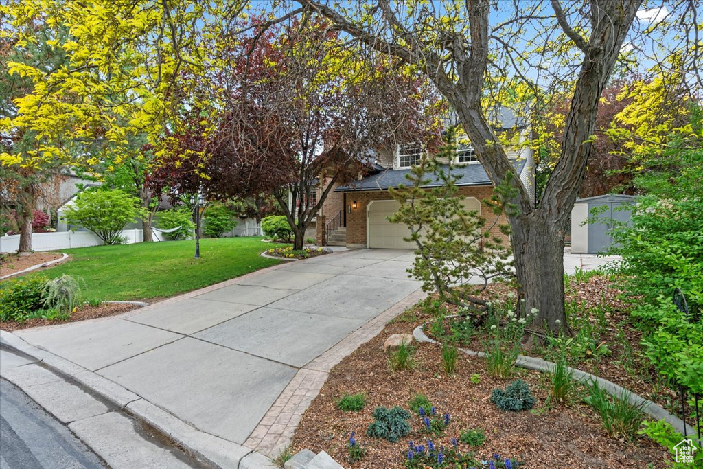 Obstructed view of property featuring fence, an attached garage, brick siding, driveway, and a front lawn