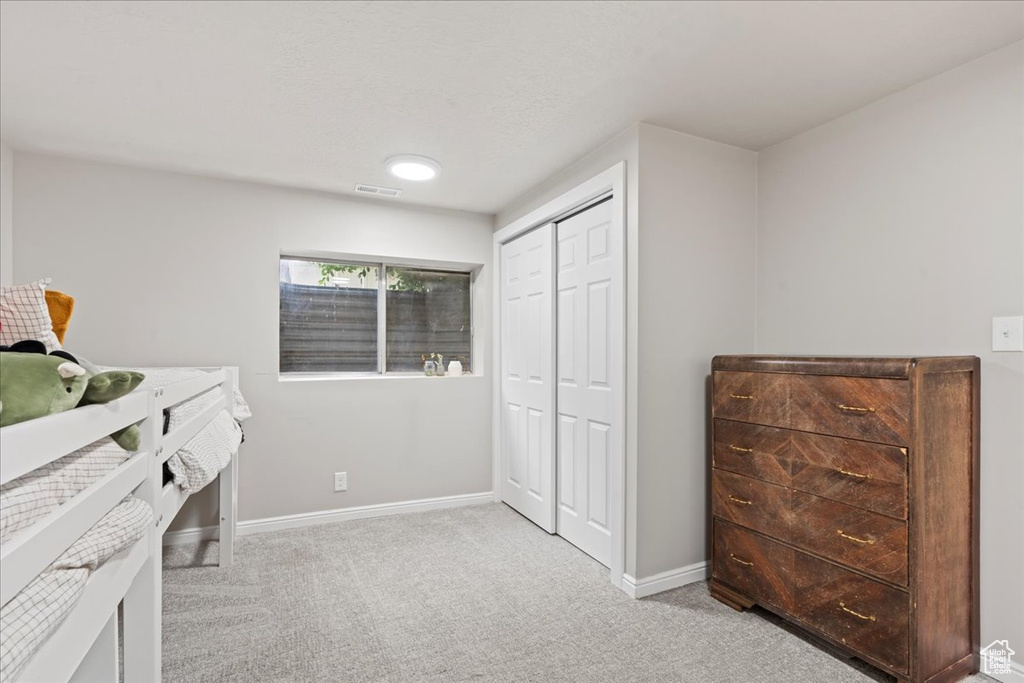 Carpeted bedroom featuring baseboards, a closet, and visible vents