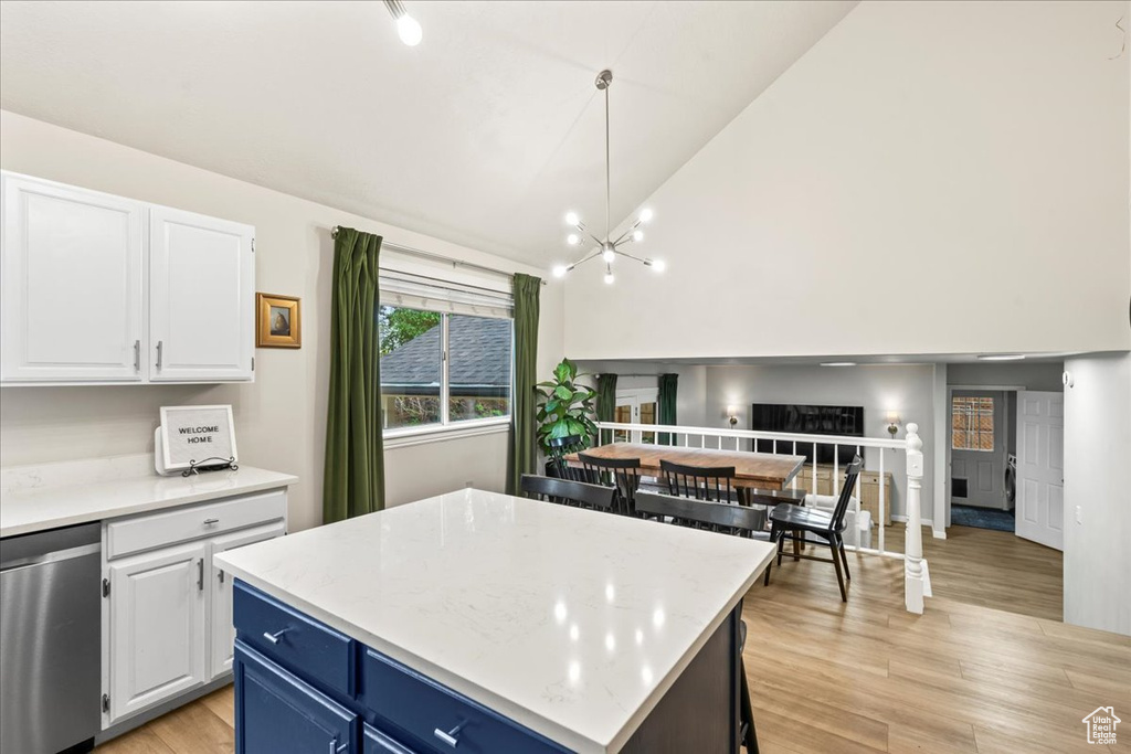 Kitchen with dishwasher, an inviting chandelier, white cabinetry, blue cabinetry, and light wood-type flooring
