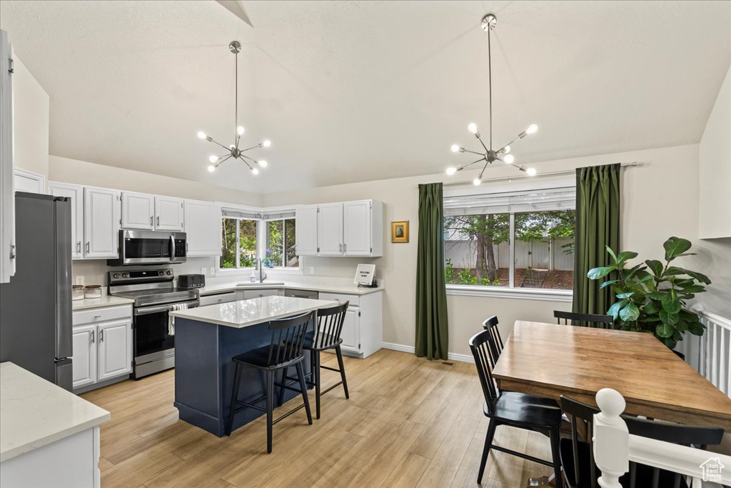 Kitchen with lofted ceiling, a notable chandelier, stainless steel appliances, and a sink