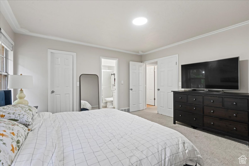 Bedroom featuring light colored carpet, crown molding, and ensuite bath