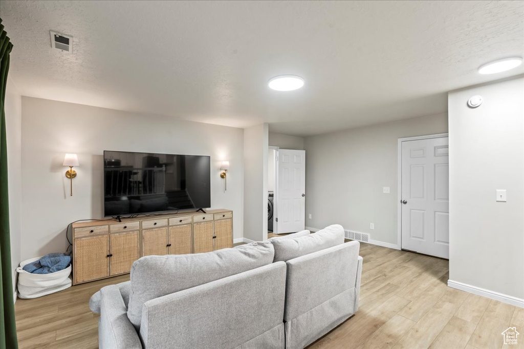 Living area featuring baseboards, light wood-style flooring, and visible vents