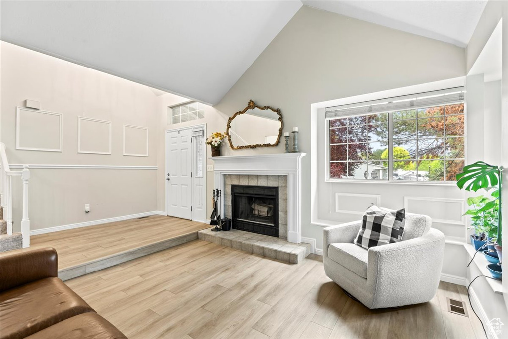 Living room featuring baseboards, a fireplace, visible vents, and wood finished floors