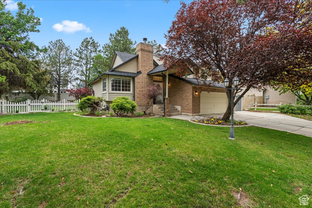 View of front of house featuring fence, a front lawn, a chimney, and driveway