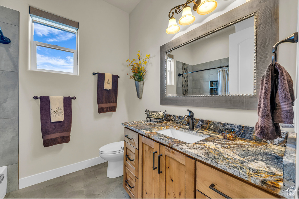 Bathroom with vanity, curtained shower, toilet, baseboards, and tile patterned floors