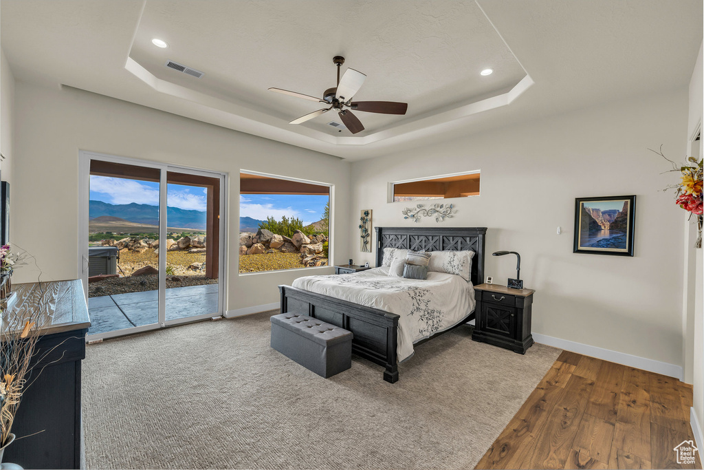 Bedroom featuring visible vents, wood finished floors, baseboards, access to outside, and a raised ceiling
