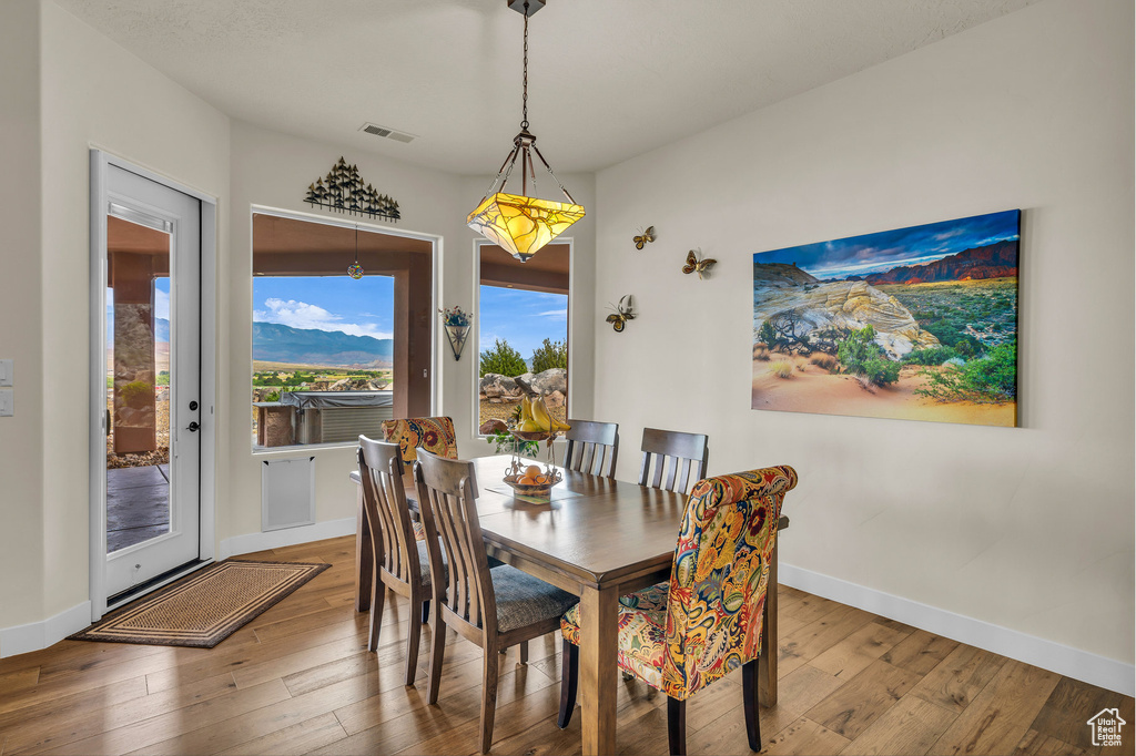 Dining room featuring wood-type flooring, baseboards, and visible vents