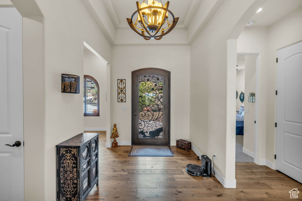 Foyer featuring an inviting chandelier, arched walkways, crown molding, and wood-type flooring