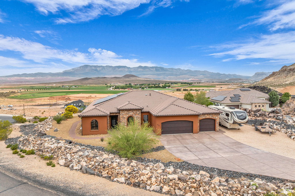 View of front of home with stucco siding, an attached garage, a mountain view, driveway, and a tile roof
