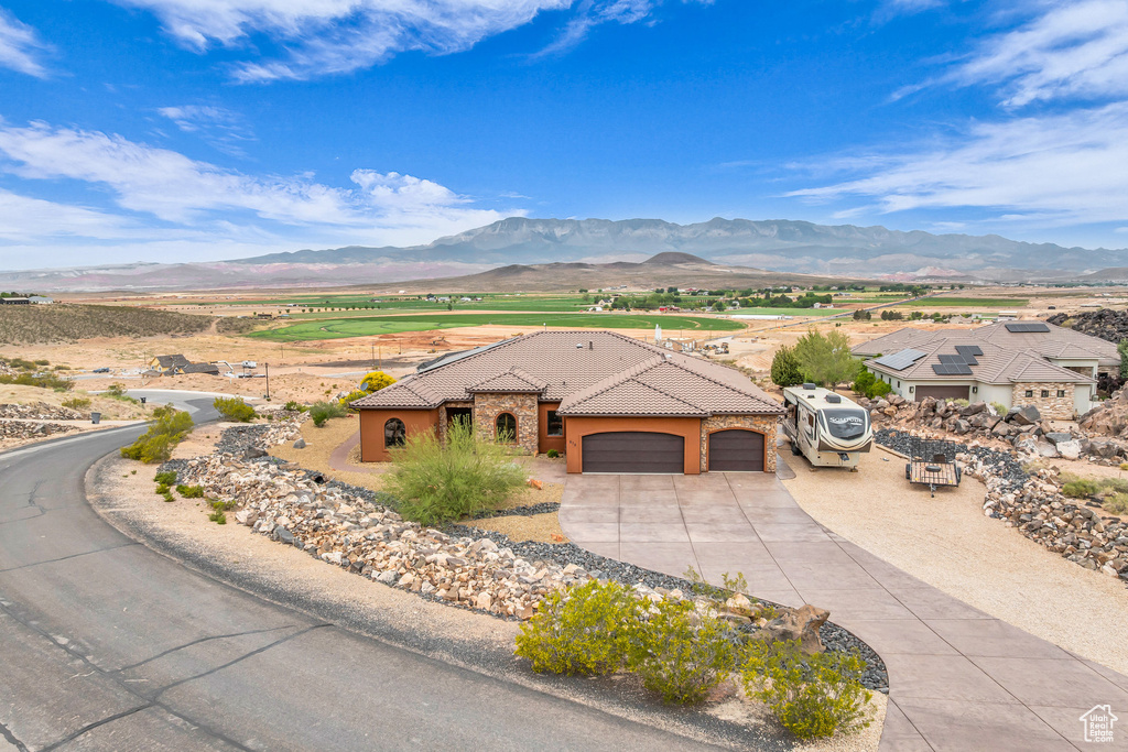 View of front facade featuring an attached garage, a tile roof, stucco siding, a mountain view, and concrete driveway