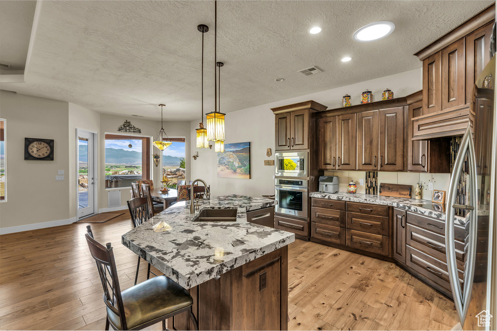 Kitchen featuring a sink, appliances with stainless steel finishes, a breakfast bar, and a textured ceiling