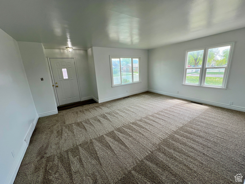 Carpeted entryway featuring baseboards and visible vents