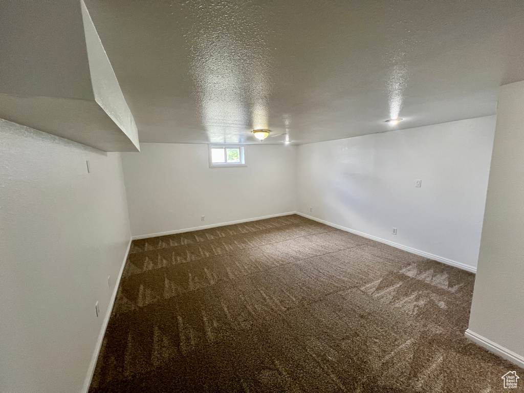 Below grade area with a textured ceiling, carpet, and baseboards