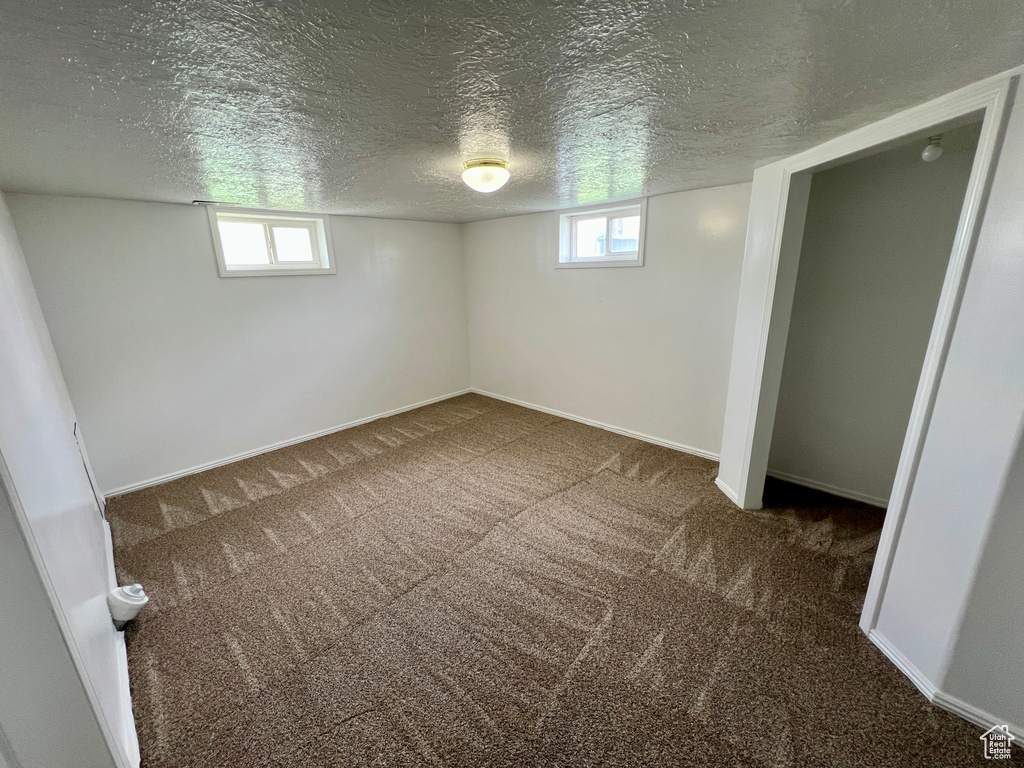 Below grade area featuring a textured ceiling, carpet flooring, and baseboards