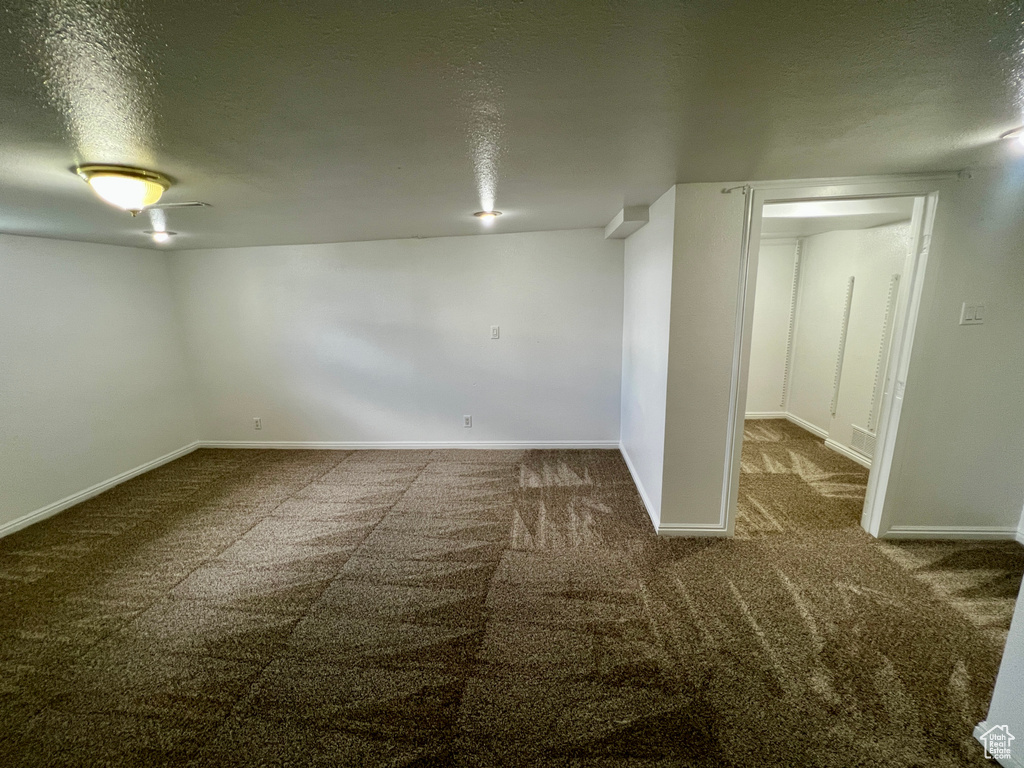 Basement with a textured ceiling, carpet floors, and baseboards
