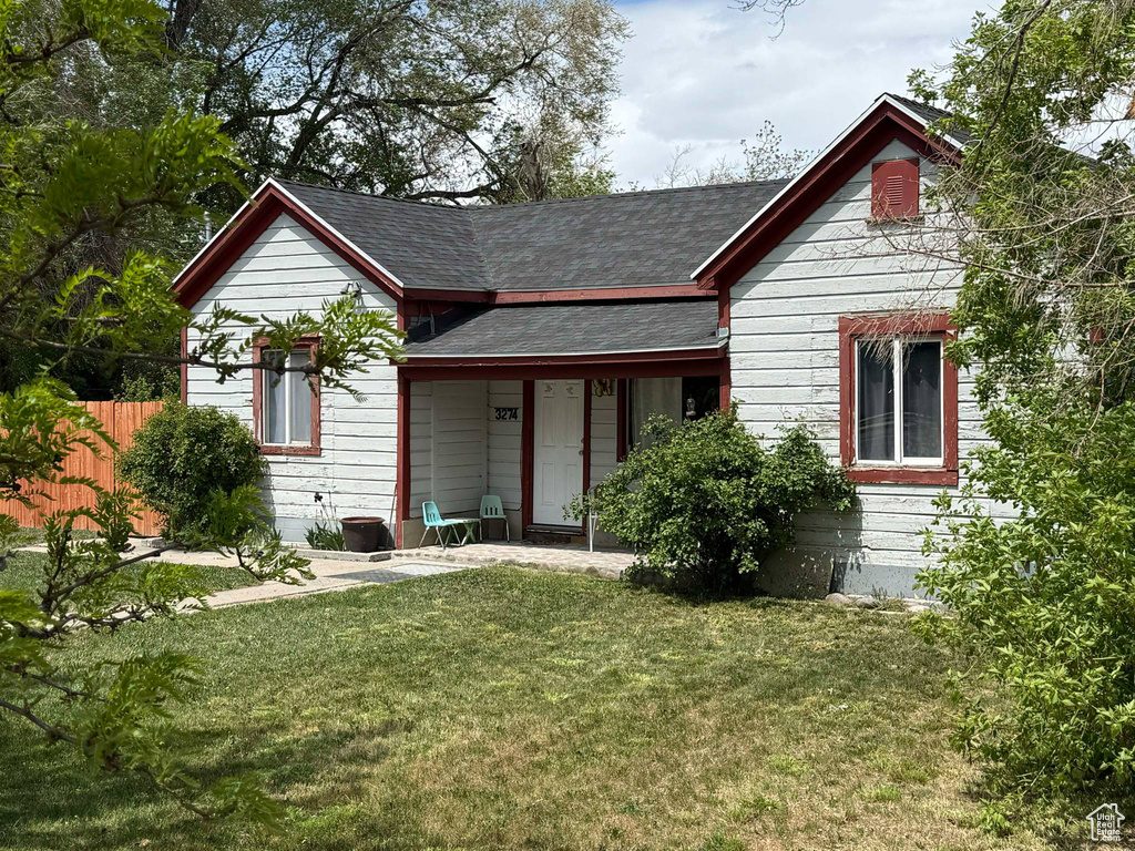 Back of property with a lawn, roof with shingles, and fence