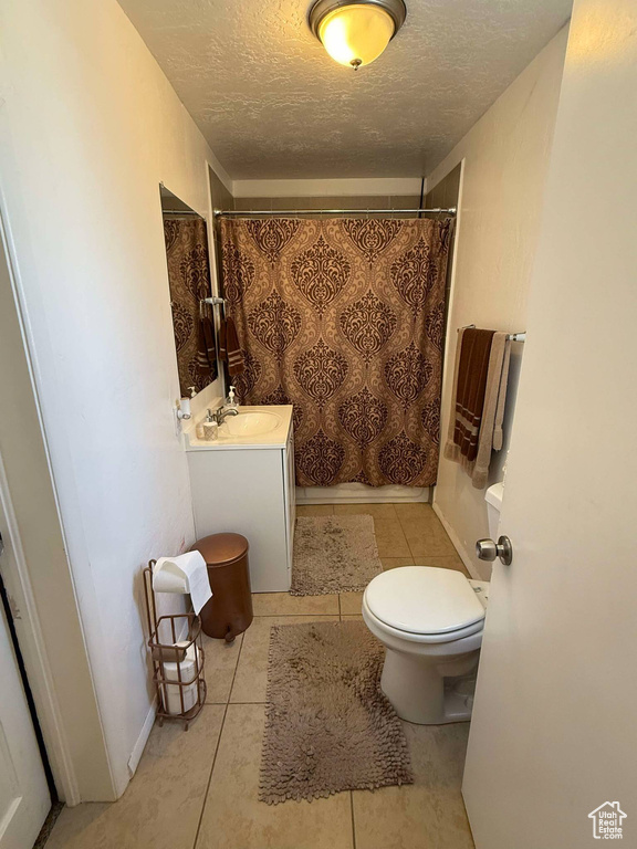 Full bathroom with a textured ceiling, a shower with curtain, toilet, tile patterned floors, and vanity