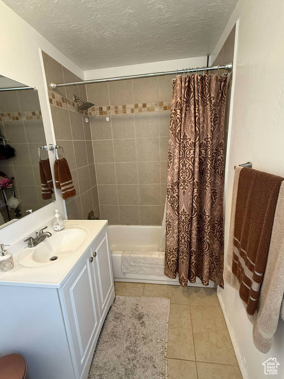 Full bath featuring shower / bathtub combination with curtain, a textured ceiling, tile patterned flooring, and vanity