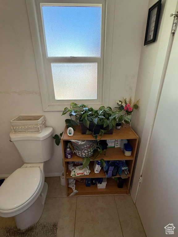 Half bathroom with baseboards, toilet, and tile patterned flooring
