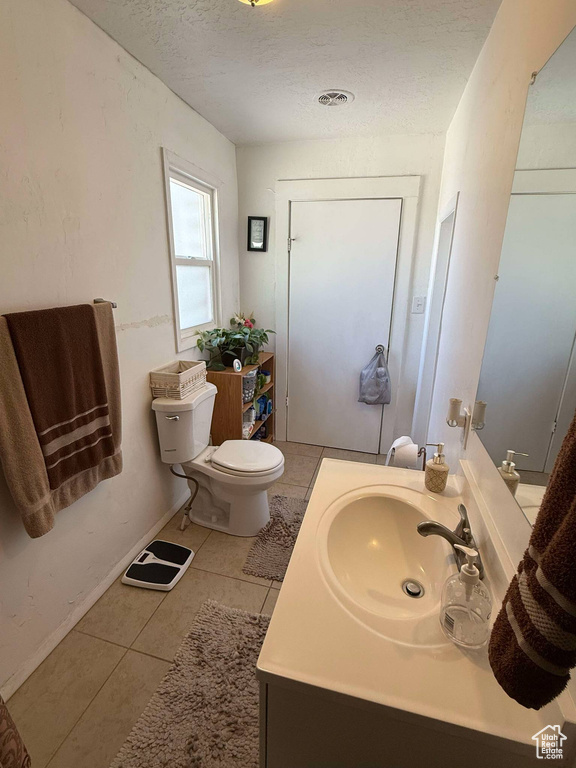 Bathroom with a textured ceiling, vanity, toilet, and tile patterned flooring