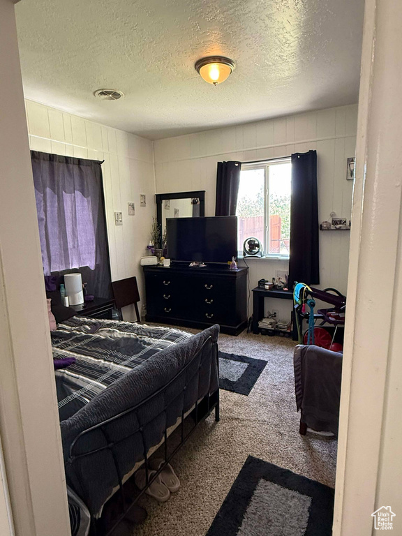 Bedroom with visible vents, a textured ceiling, and carpet